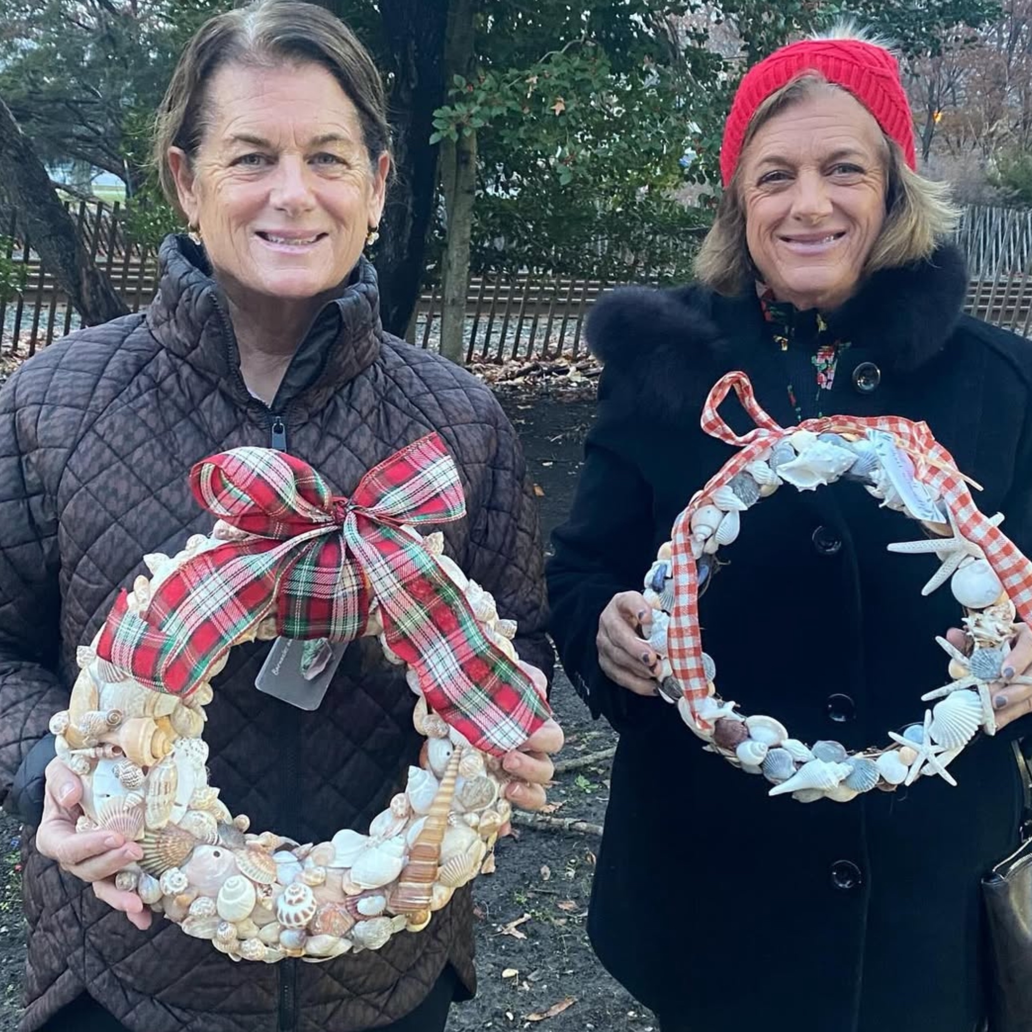 Two customers holding shell wreaths with plaid ribbons